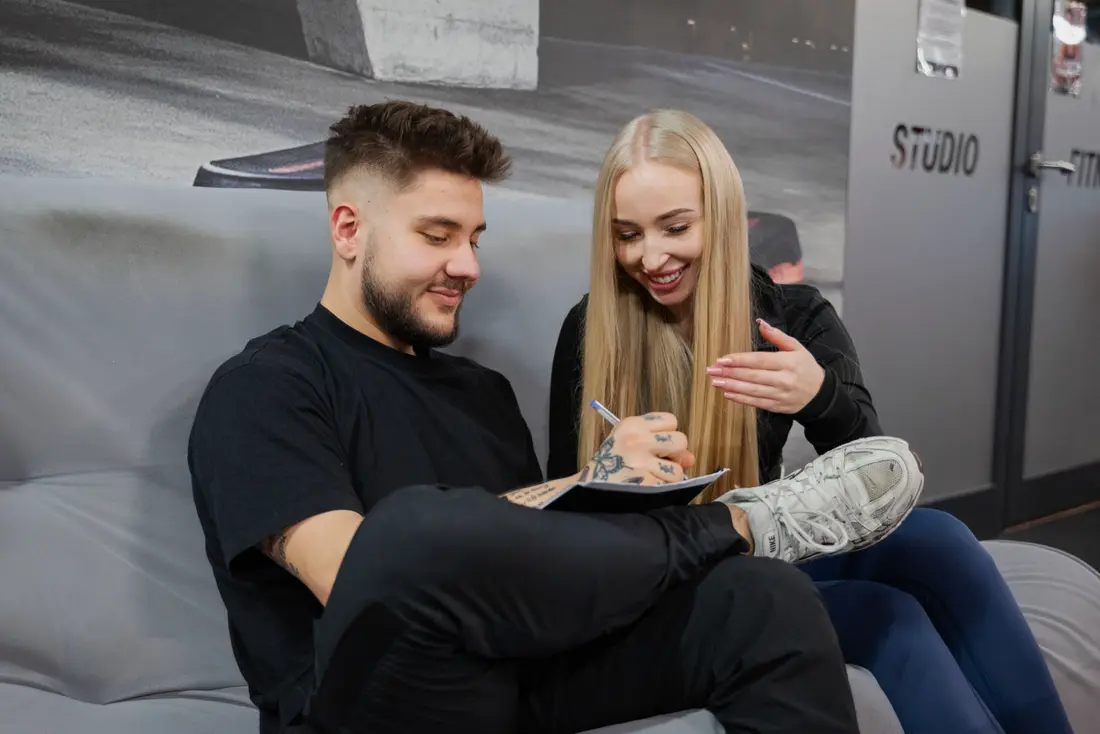 Trener rozmawia z podopieczną i przegląda z nią notatki przed treningiem